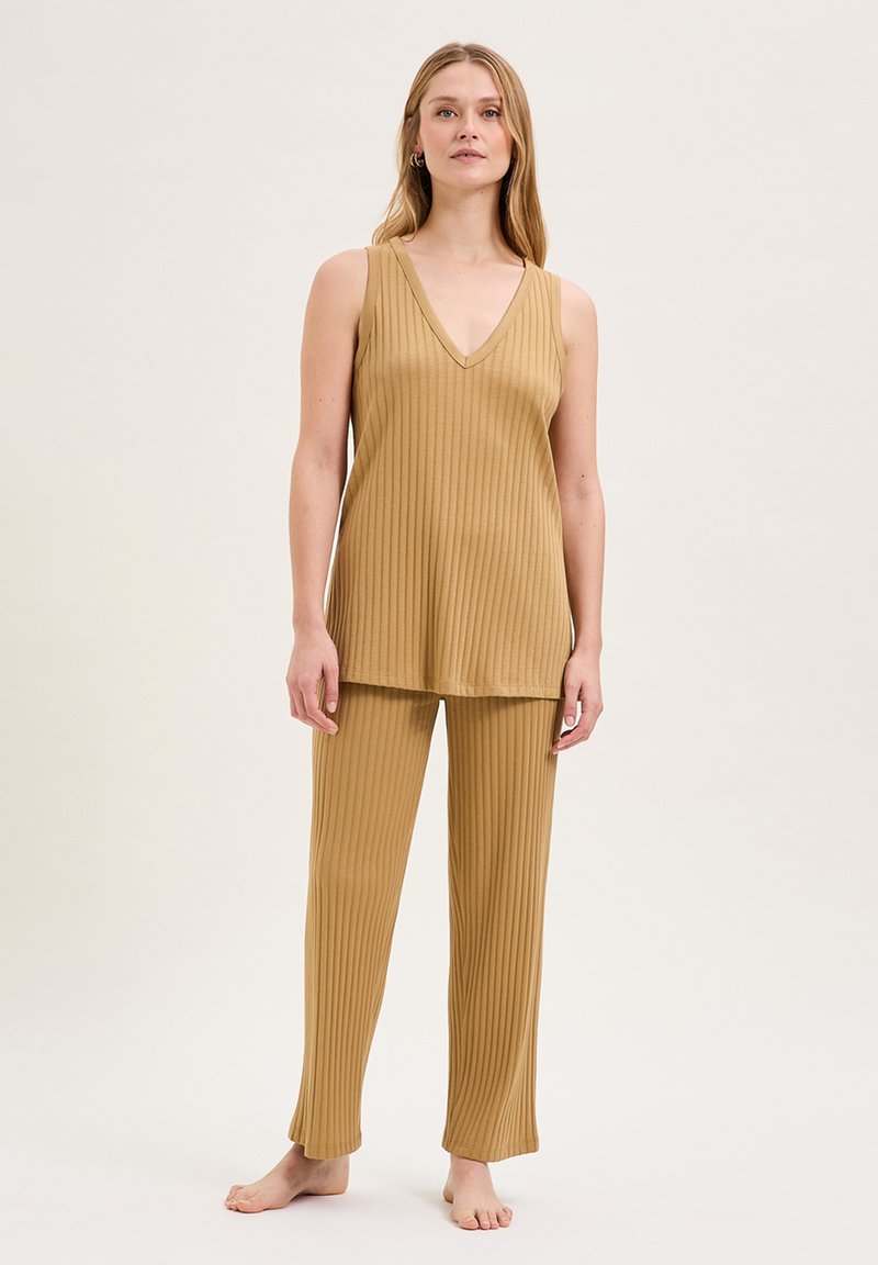 Ensemble de nuit beige, côtelé, composé d'un haut sans manches avec un décolleté en V et d'un pantalon droit assorti. Texture douce, coupe décontractée.