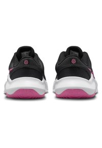 Pár černých a růžových sportovních bot z pohledu zezadu s bílými mezipodešvemi a texturovanými růžovými podrážkami.