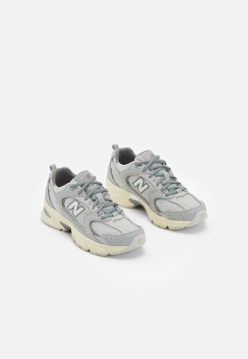 Grey athletic shoes made of mesh and synthetic materials, featuring a thick cream sole, padded collar, and reflective accents.