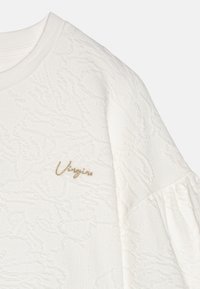 Suéter blanco texturizado con patrones en relieve y un escote redondo. Presenta un logo bordado en dorado en el lado izquierdo del pecho.