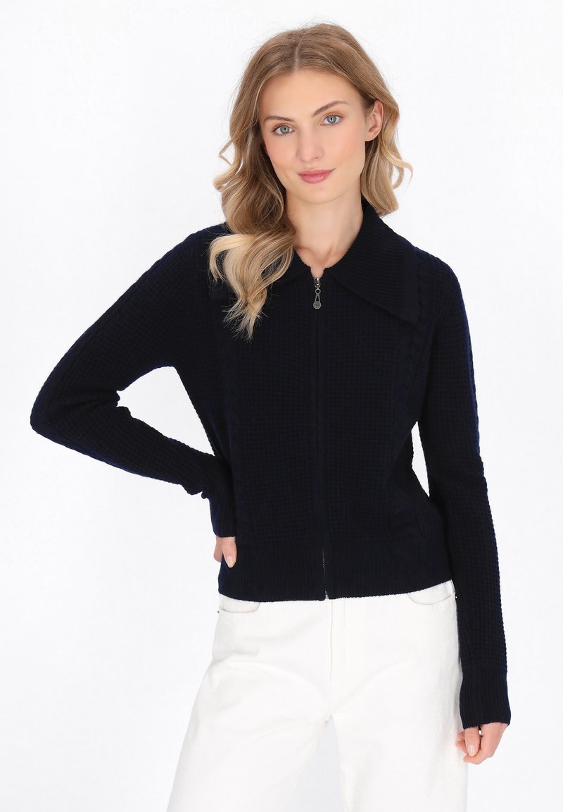Cardigan blu navy con zip, dotato di texture a coste, ampio colletto e maniche lunghe, progettato con pannelli laterali per una vestibilità strutturata.