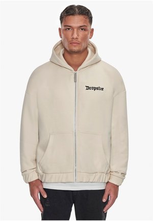 Cream zip-up hoodie with a front pocket, ribbed cuffs, and embroidered "Dropsize" logo in black across the chest. Soft, textured fabric.