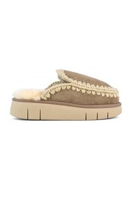 Pantofole in camoscio di colore tan, con un interno morbido e una rifinitura intrecciata lungo la parte superiore. Suola in gomma spessa con texture scanalata.