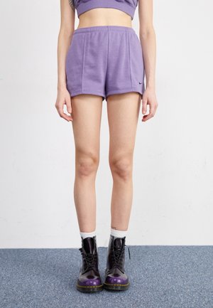 Shorts en coton violet avec une taille élastique, dotés d'une poche latérale et d'un petit logo noir. Associés à des bottes de combat noires et violettes.
