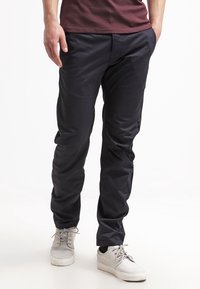 Mörkblå chinos i smidigt tyg, med en slim fit-design och sidfickor, i kombination med vita skor.