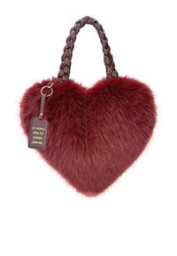 Borsa a forma di cuore in pelliccia sintetica rossa con manico intrecciato marrone e un'etichetta in pelle che recita "CI VUOLE MOLTO CUORE CON ME."