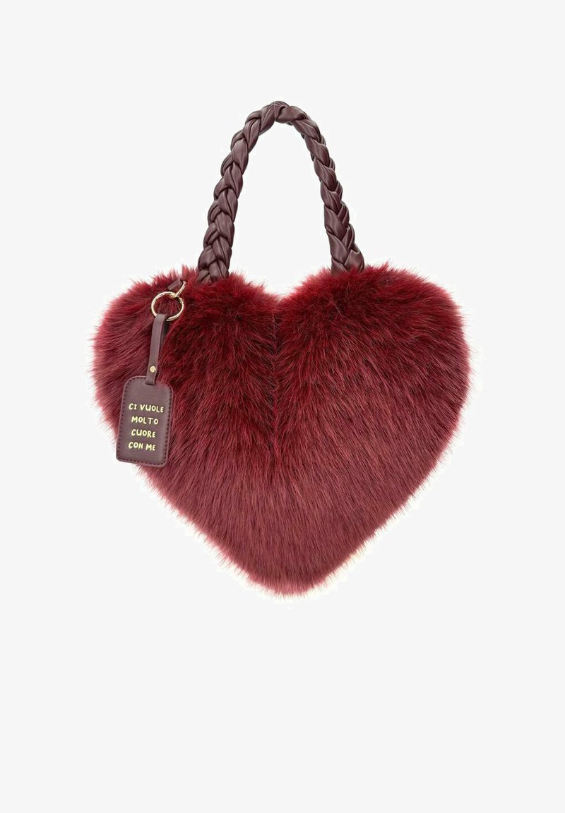 Borsa a forma di cuore in pelliccia sintetica rossa con manico intrecciato marrone e un'etichetta in pelle che recita "CI VUOLE MOLTO CUORE CON ME."