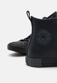 Zapatillas altas negras de lona texturizada, con un parche de logo redondo, diseño con cordones y suela de goma con patrón de zigzag.