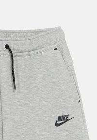 Γκρι φόρμες φτιαγμένες από απαλό βαμβακερό μείγμα. Διαθέτουν μαύρο κορδόνι, πλαϊνές τσέπες και μαύρο λογότυπο Nike στην αριστερή πλευρά.