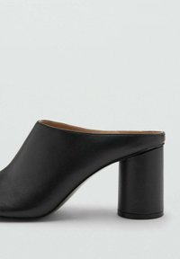 Mule abierto de piel negra con una silueta redondeada y un tacón cilíndrico grueso, con textura suave y sin adornos visibles.