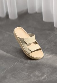 Bežna natikača na platformi s dvema nastavljivima Velcro trakama, gladka površina in teksturiran gumijast podplat. Minimalističen dizajn z zaobljeno obliko.