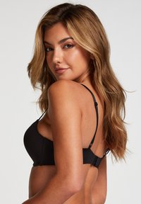 Black bra with adjustable thin straps, smooth fabric, underwire support, and a hook-and-eye back closure, featuring a seamless design.