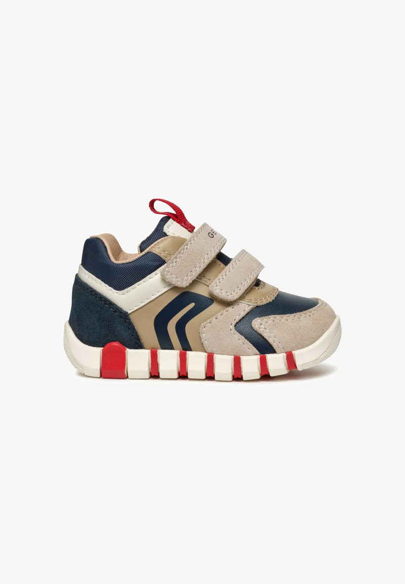 Scarpe sportive per bambini con una combinazione di colori beige, blu navy e rosso. Presentano materiali in suede e sintetici, due cinturini in velcro e una suola texturizzata.