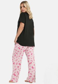 Svart bomullströja med korta ärmar som matchas med ljusrosa pyjamasbyxor med olika rosa tryckmönster, inklusive stjärnor och kaktusar.