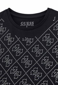 T-shirt en coton biologique noir avec un motif décoratif de strass argentés disposés en formes de diamants. Encolure ronde.