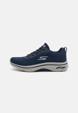 Navy mesh athletic shoes with a textured surface, gray rubber sole, and supportive arch design. Features laces and logo on the side.
