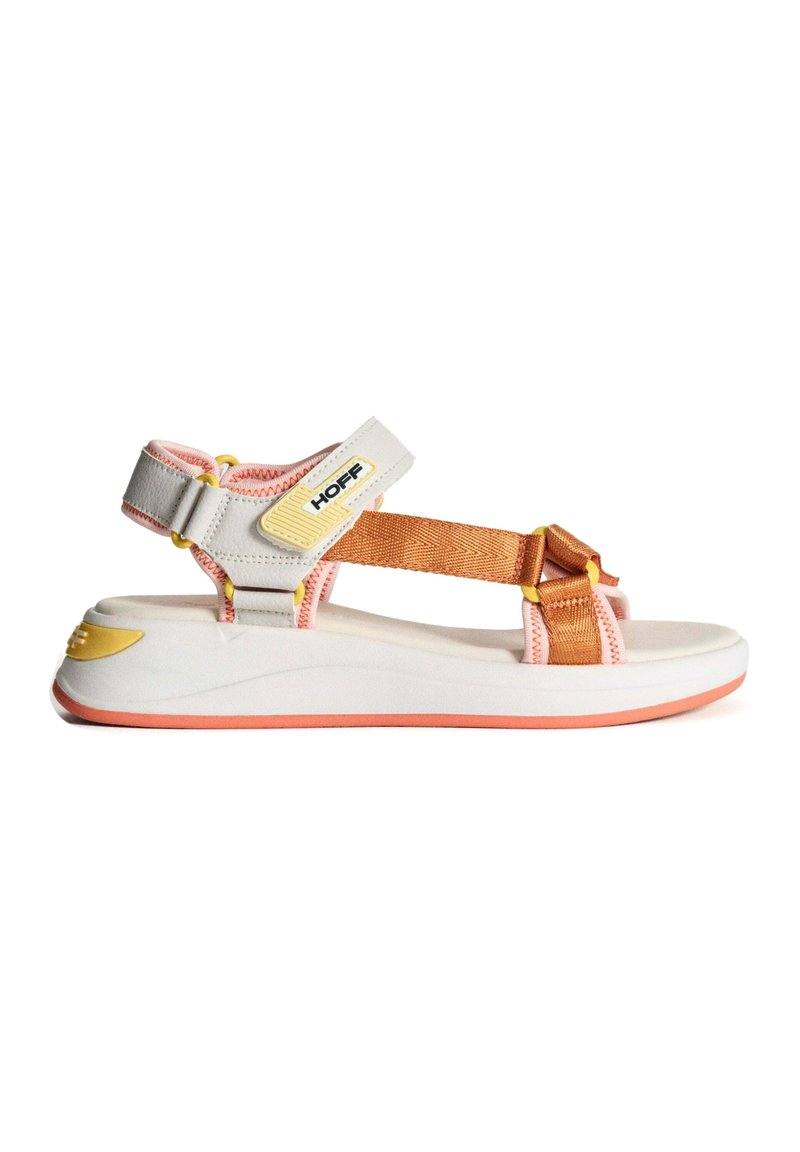 Sandalias con un diseño blanco y naranja: correas de nailon con acentos amarillos, una suela ligeramente curvada y un ribete inferior de goma rosa.