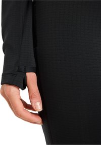 Zwarte kleding met lange mouwen van een textuurstof, voorzien van een duimopening in de manchet en een nauwsluitend ontwerp, dat de handpositie accentueert.