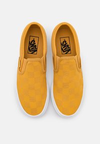 Scarpe slip-on a scacchi gialli con tomaia in tela e suola in gomma bianca. Presentano il logo Vans sulla soletta. Senza lacci né chiusure.