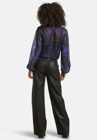 Sheer black and blue floral blouse with billowy sleeves, paired with high-waisted black leather wide-leg pants.