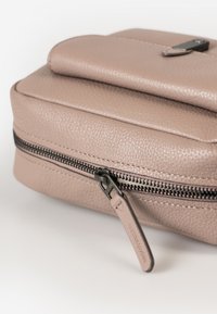 Borsa in pelle beige con finitura testurizzata, dotata di chiusura a zip e un piccolo dettaglio in metallo scuro sulla parte superiore.