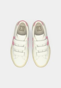 Ζευγάρι λευκά αθλητικά παπούτσια με ροζ λεπτομέρειες και τρεις ιμάντες βέλκρο, απεικονιζόμενα από πάνω σε λευκό φόντο.