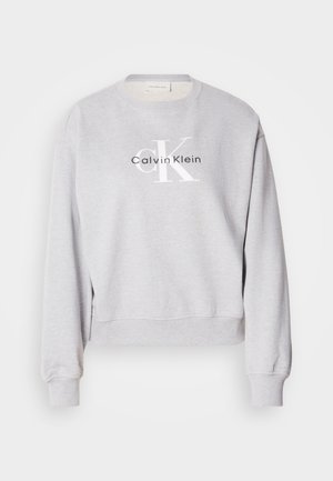 Felpa grigia con collo a giro, maniche lunghe e polsini a costine. Presenta un logo stampato: "Calvin Klein" e "cK" in bianco e nero.