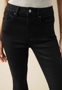 Zwarte spijkerbroek met een aangesloten ontwerp, gemaakt van denim, met een vijfzakkenlayout, een metalen knoopsluiting en subtiele stiksels.