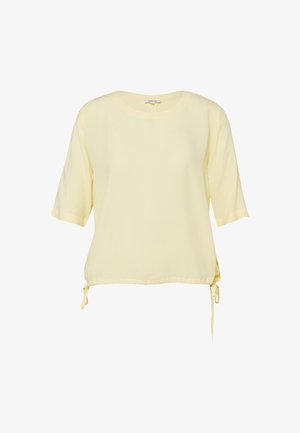 Hellgelbe kurzärmelige Bluse mit rundem Ausschnitt und verstellbaren Kordeln am Saum vor weißem Hintergrund.