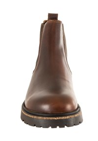 Botín de cuero marrón hasta el tobillo con paneles laterales elásticos, puntera redonda y una resistente suela de caucho negro con un patrón texturizado.