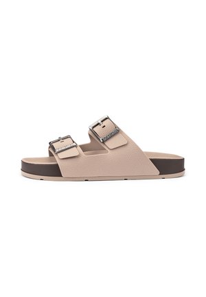 Beige open-toe slide sandal with two adjustable silver buckles and a dark brown sole, shown from the side on a white background.