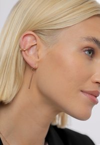 Naušnice na viseću s križom od ružičastog zlata s tankim, izduženim dizajnom trake i teksturiranim završetkom, u paru s glatkim, zaobljenim ušnim prstenom.