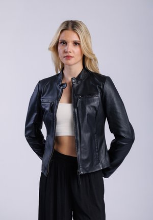 Black leather jacket with a collar and front zip. Features two zippered chest pockets and smooth texture. Worn over a white crop top.