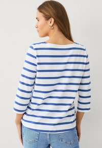 Witte katoenen blouse met blauwe horizontale strepen, 3/4 mouwen en een brede halslijn. De achterkant heeft een gebogen zoom en een ontspannen pasvorm.