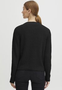 Čierny rebrovaný sveter s dlhými rukávmi, textilným materiálom a mierne skráteným lemom. Chrbát má jednoduchý, zaoblený výstrih.
