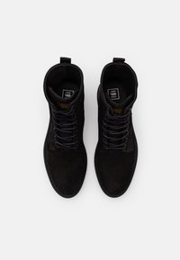 Botines de ante negro con punta redonda, cordones planos y asa de tirón. Presentan un upper texturizado y suela de goma duradera. Detalle del logo en contraste en el interior.