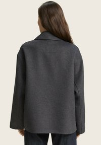 Grijze wolmix jas met een kraag, lange mouwen en een iets oversized pasvorm. De achterkant heeft een vierkante patchdetail.