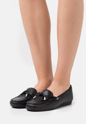 Mocassins en cuir noir avec bout rond, accents en dentelle et quincaillerie argentée. Semelle plate, design minimaliste et texture lisse.