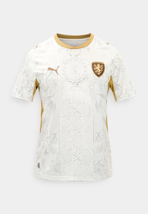 Valge spordisärk kuldsete detailidega, peene mustrilise tekstuuriga, Puma logo paremal rinnal ja kuldne lõvitiib vasakul rinnal.