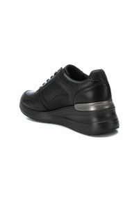 Zapatilla deportiva negra con parte superior texturizada, acentos de cuero suave, tacón redondeado y detalles de hardware en plata. Diseño con cordones y cuello acolchado.
