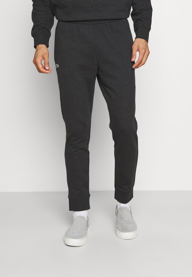 Mörkgrå joggerbyxor med elastisk midjeband, tapered bendesign och ribbade cuffar. Har en liten logodetalj framtill.