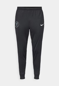 Sorte Nike træningsbukser med tapered ben, elastisk talje og ribbrændsel. Har et Chelsea FC-logo på venstre lår.