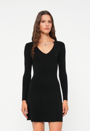 Black long-sleeve dress with a V-neckline, fitted silhouette, and smooth texture. A minimalistic design with no visible patterns or accents.