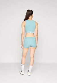 Light blue athletic crop top with a matching high-waisted short. Features a supportive fit and "Nike Pro" branding on the waistband.