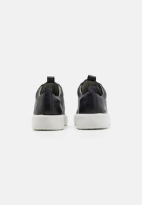 Sorte lær sneakers med teksturert overflate, lav profil, hvite gummisåler og trekkfliker bak for enkel påføring.