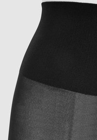 Mustat korkeavyötäröiset legginsit, joissa on ribbikuvioitu yläosa ja sileä, puoliksi läpinäkyvä lahkeiden osa. Suunniteltu mukavuuden ja istuvuuden takaamiseksi.