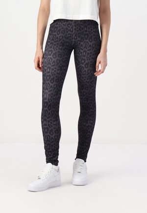 Black leggings with a textured leopard print pattern, featuring a smooth fabric and a fitted design, paired with white sneakers.