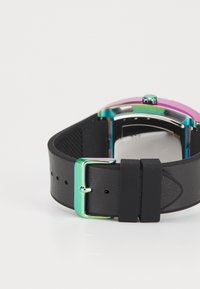 Bracelet de montre en caoutchouc noir avec une boucle métallique de couleur arc-en-ciel. Le cadran de la montre présente une lunette colorée et un dessous texturé.