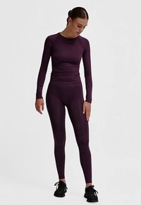 Långärmad sporttopp och tajta leggings i mörklila tyg, med texturerad detaljering och en smal passform.