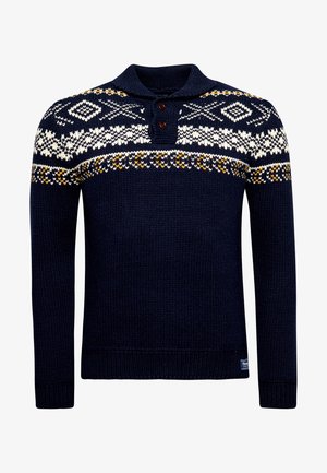 Marineblauwe gebreide trui met witte en gele geometrische patronen over de borst en schouders, voorzien van een kraag met twee knopen.